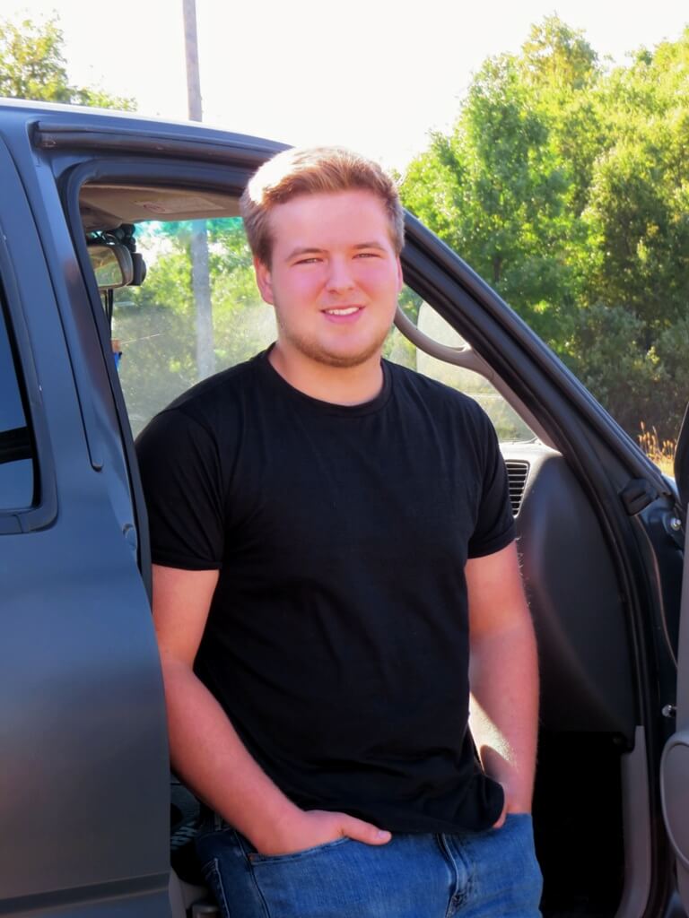 Senior Photo of boy with black shirt sitting in his truck, hands in pockets Senior Photo of black shirt and smile, sitting in the side of his truck