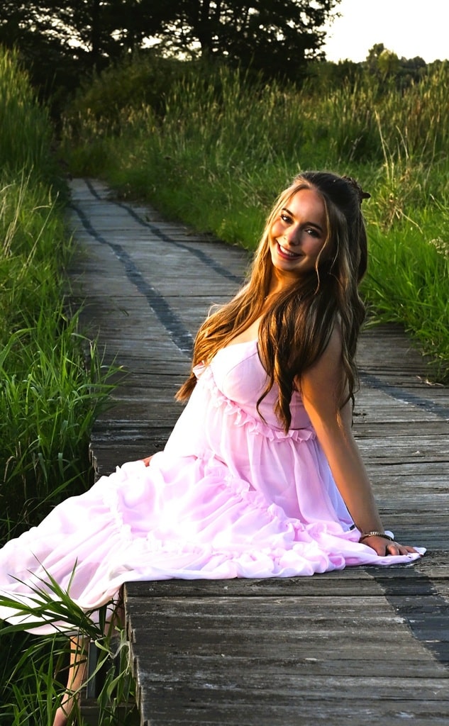 Senior photo of girl in pink dress at St Johns with big smile on her face Senior photo of girl in pink dress with a big smile on the walking path at St Johns and leaning back