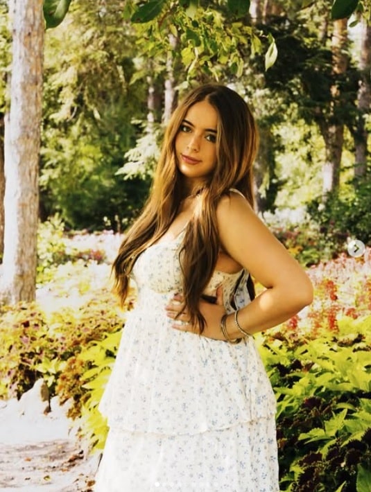Senior Photo with white dress and hands on hips no smile Senior Photo of girl with hands on hip and white dress in the sun, over the shoulder look